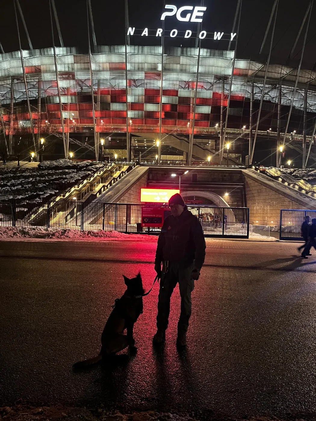 Przewodnik K9 z&nbsp;psem przed PGE Narodowym w&nbsp;nocy